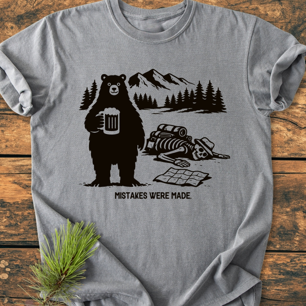 Mistakes Were Made - Vintage Wash Tee featuring a cartoon bear with beer, pine and mountain backdrop, hiker skeleton, and humorous caption. Garment-dyed for comfort, relaxed fit, durable stitching.