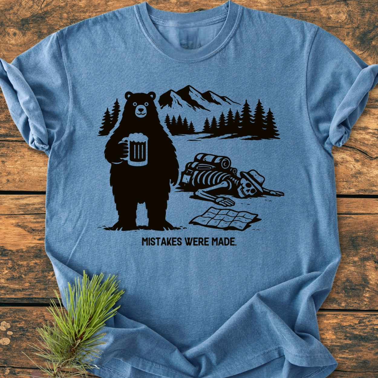 Mistakes Were Made - Vintage Wash Tee features a bear with a beer, a mountain backdrop, and a hiker's skeleton with an open map, capturing a humorous outdoor mishap.