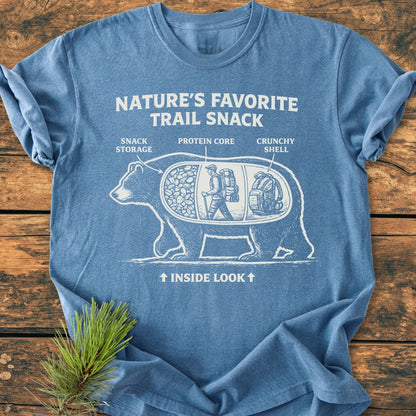 Trail Snack - Vintage Wash Tee featuring a playful bear illustration with labeled compartments for trail snacks, printed on a soft-blue garment-dyed, 100% ring-spun cotton T-shirt laid on a wooden surface.