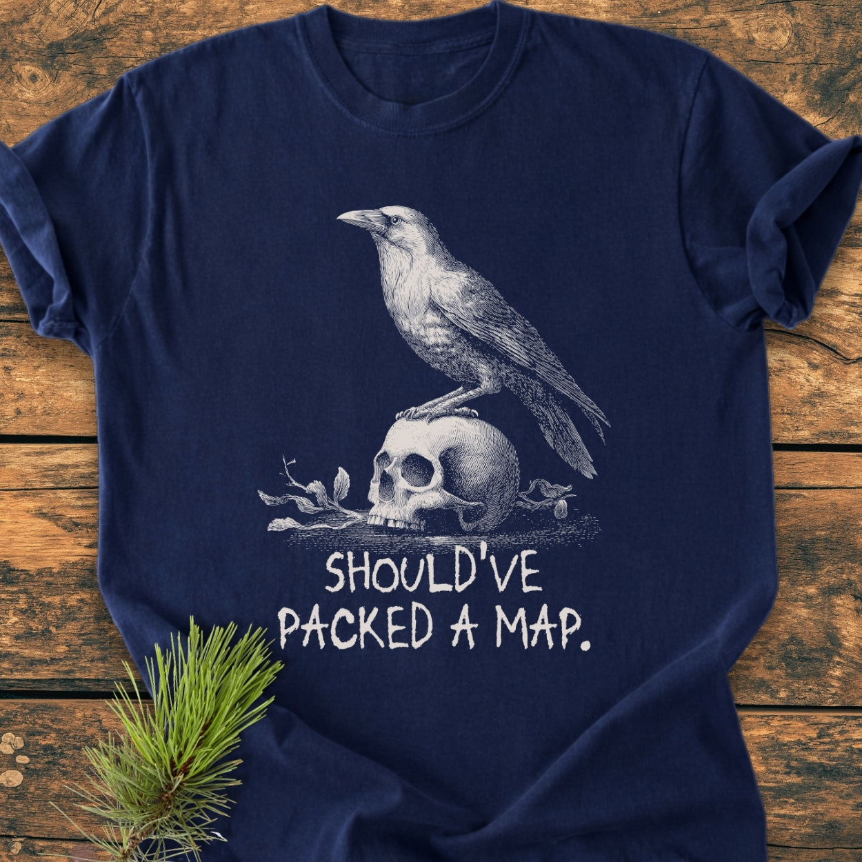 No WI-FI - Vintage Wash Tee featuring a crow atop a skull illustration with “SHOULD’VE PACKED A MAP.” caption, laid flat on a wooden surface, showcasing the garment's relaxed fit and detailed design.
