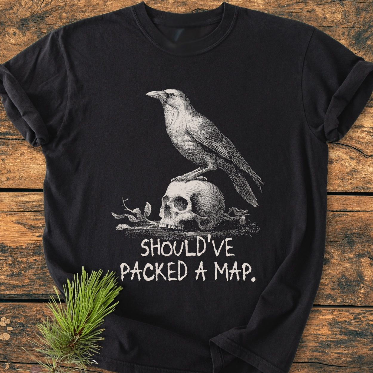 No WI-FI - Vintage Wash Tee features a crow on a skull graphic with “SHOULD’VE PACKED A MAP.” caption, laid on a rustic surface, showcasing its relaxed, durable design.