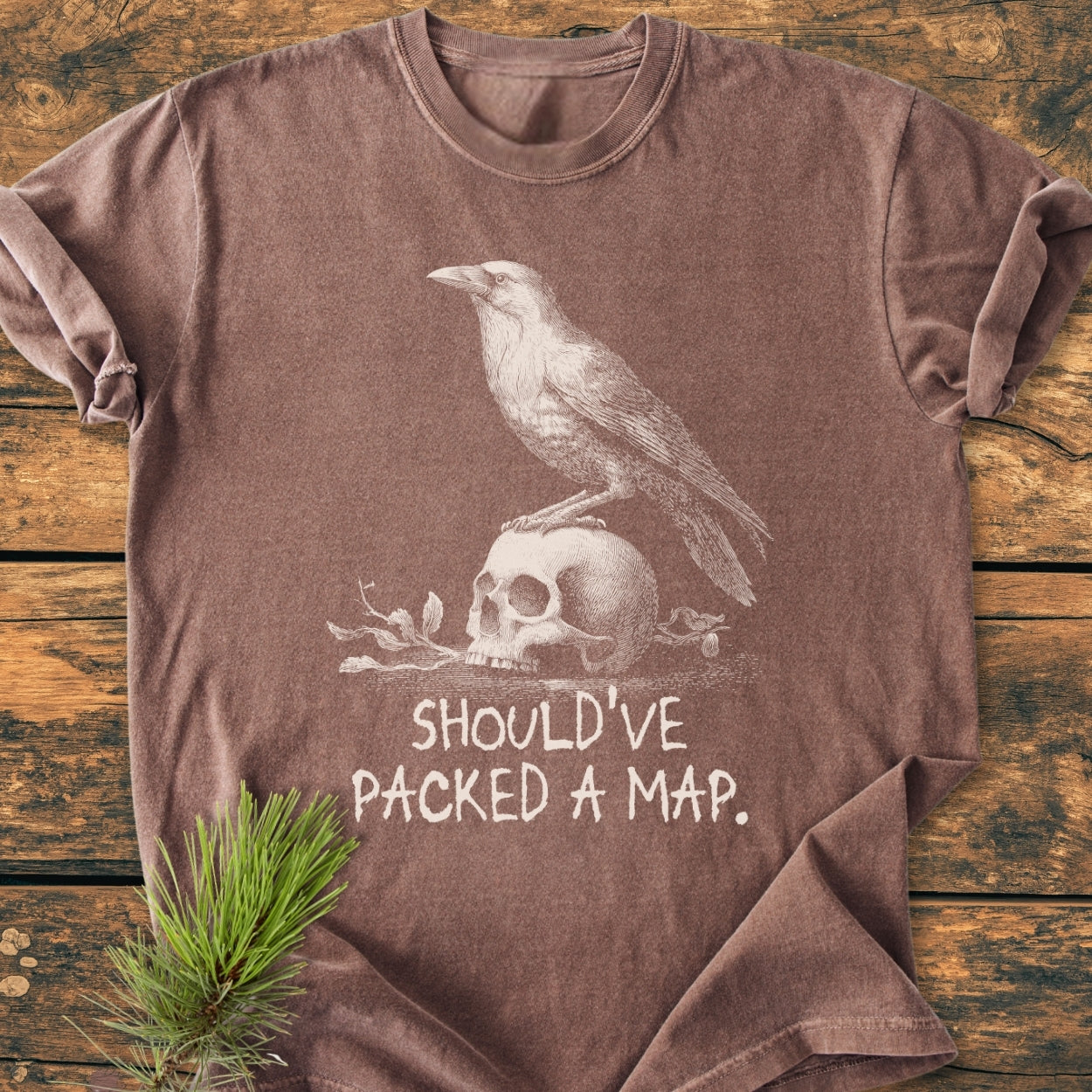 No WI-FI - Vintage Wash Tee featuring a raven on a skull design with SHOULD’VE PACKED A MAP text, laid on wood with a pine branch accent. Comfortable, soft-washed, garment-dyed cotton.