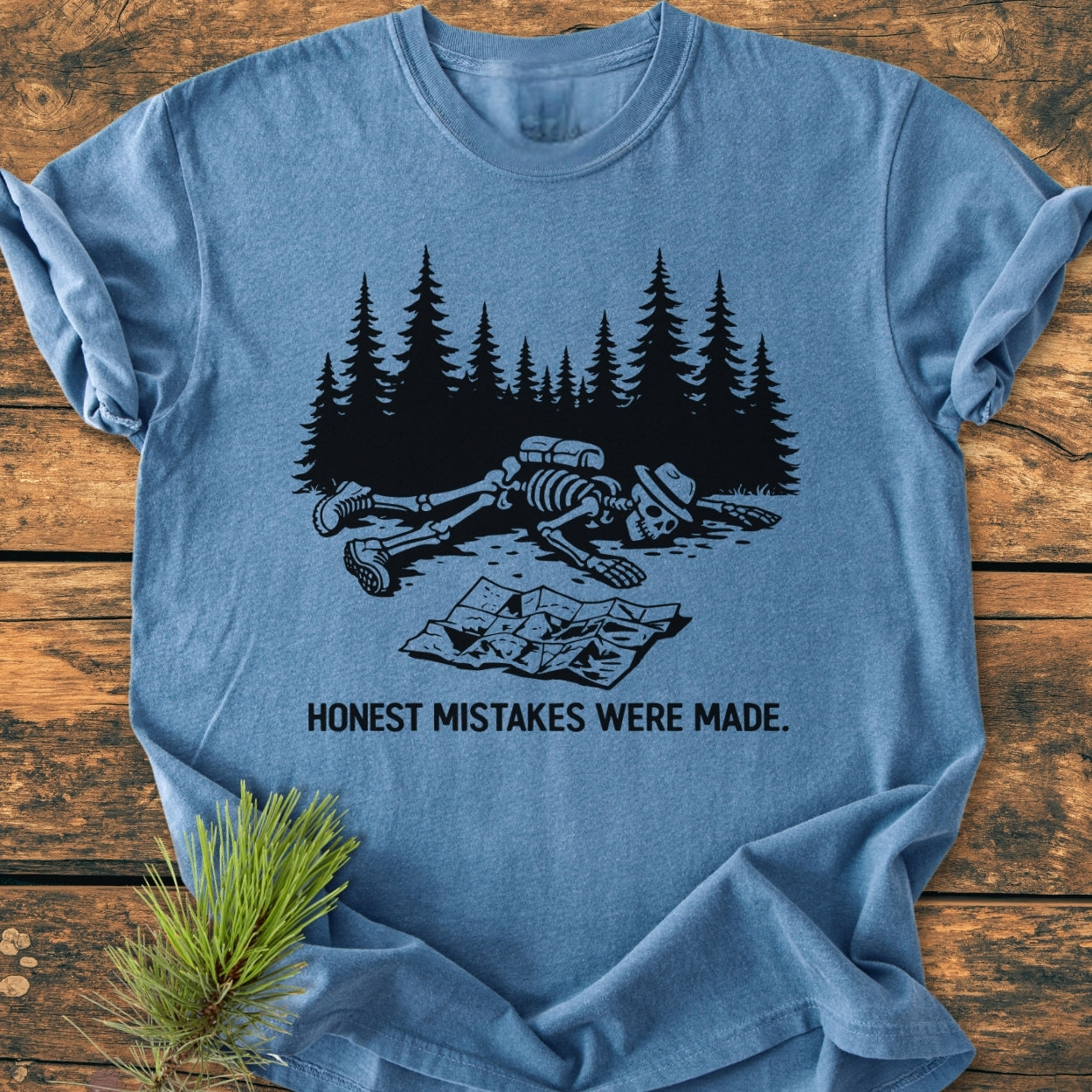 Honest Mistakes Were Made - Vintage Wash Tee featuring a skeleton illustration with “HONEST MISTAKES WERE MADE.” caption, laid on wooden surface, showcasing Comfort Colors' durable, soft-washed, relaxed fit design.