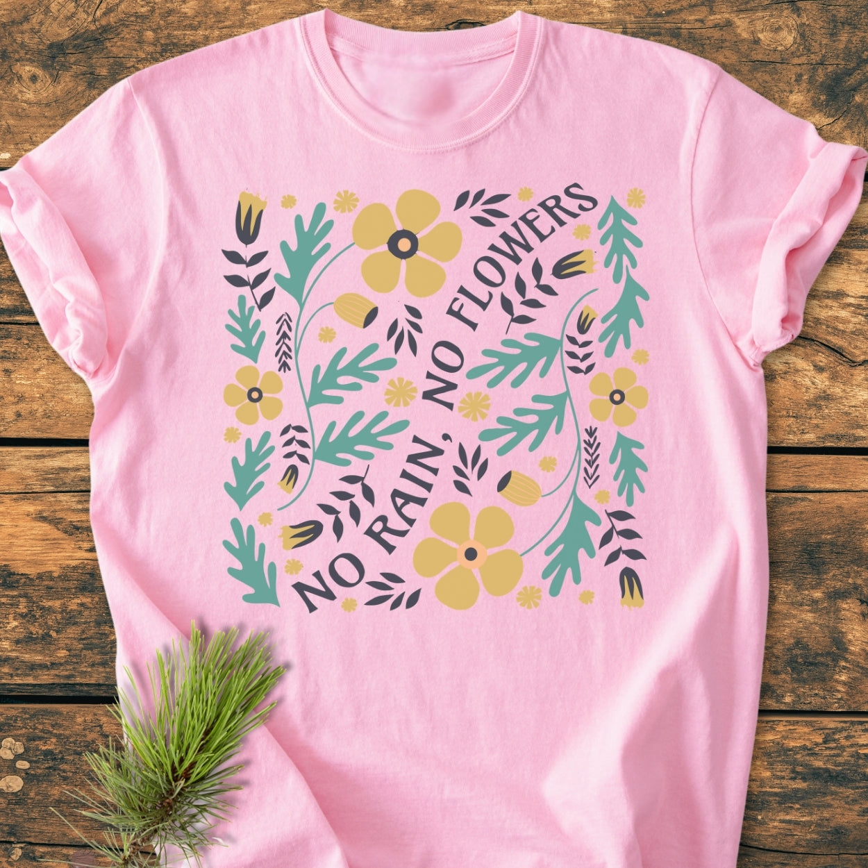 No Rain No Flowers - Vintage Wash Tee features a floral graphic with leaves and flowers surrounding the motto, laid on wood; includes a soft, relaxed fit garment-dyed in 100% ring-spun cotton.