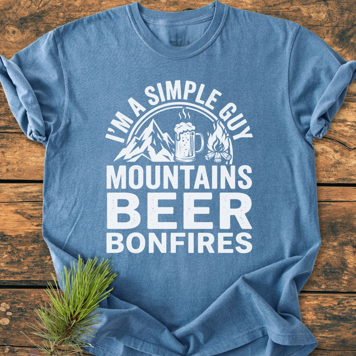 Mountains Beer Bonfires - Vintage Wash Tee, featuring bold white graphics on heather-blue, styled with a pine sprig, showcasing a relaxed fit and durable, soft-washed fabric.