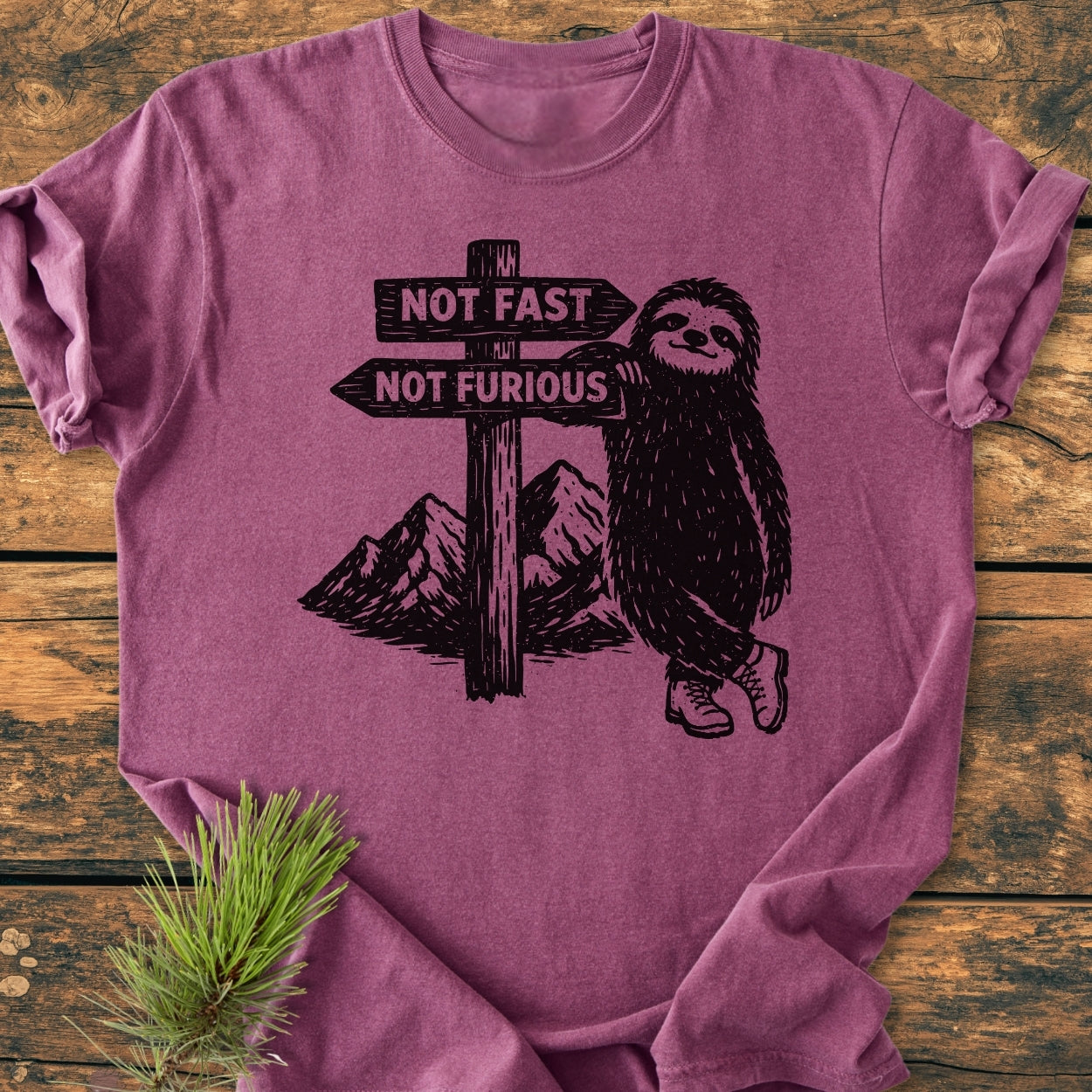 Not Fast Not Furious - Vintage Wash Tee features a sloth in hiking boots on a heather-purple shirt, leaning on a signpost with playful directions, styled with a pine sprig.