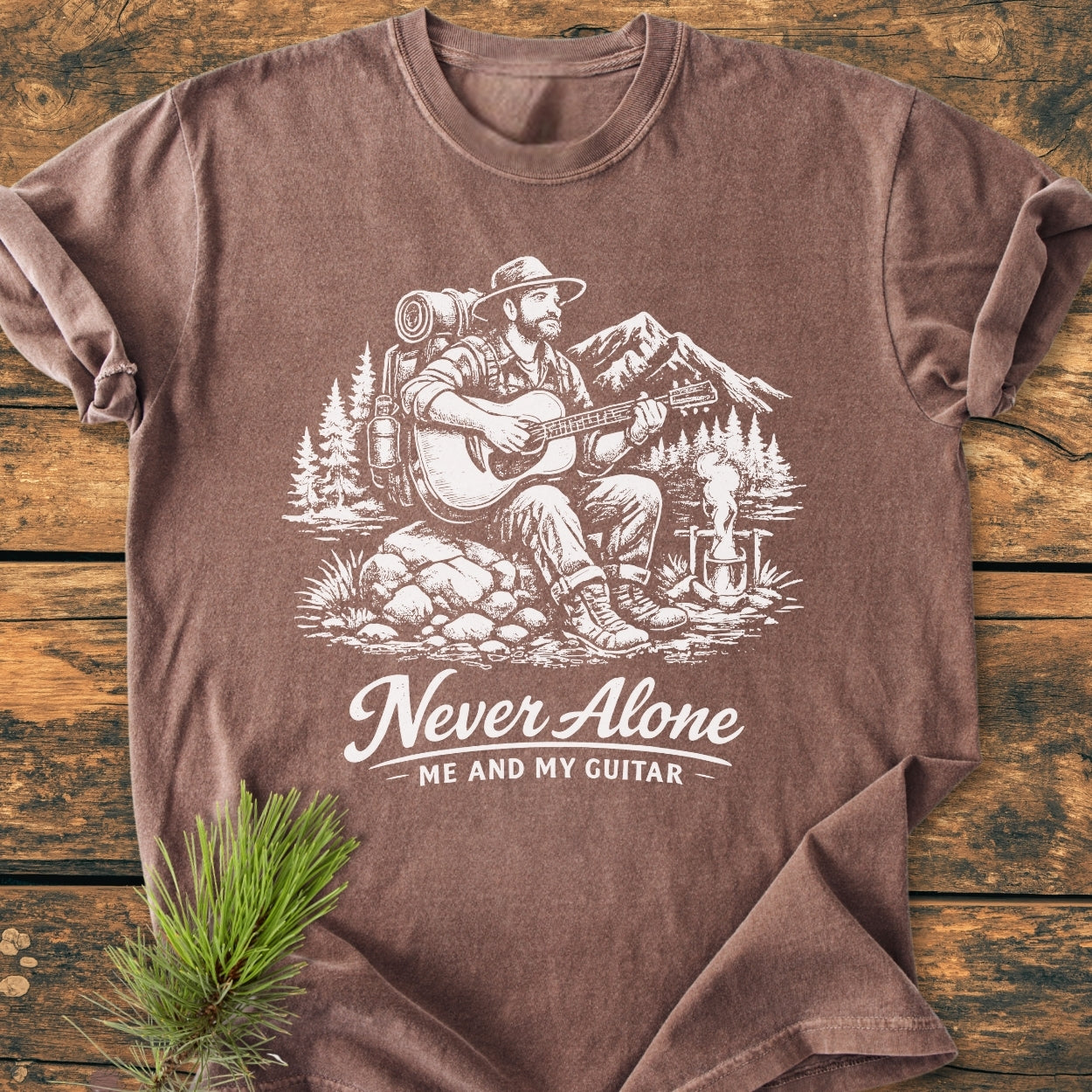 Never Alone. Me And My Guitar - Vintage Wash Tee featuring a bearded man illustration with a campfire and scenic backdrop, highlighting its soft, durable Comfort Colors design in 100% ring-spun cotton.