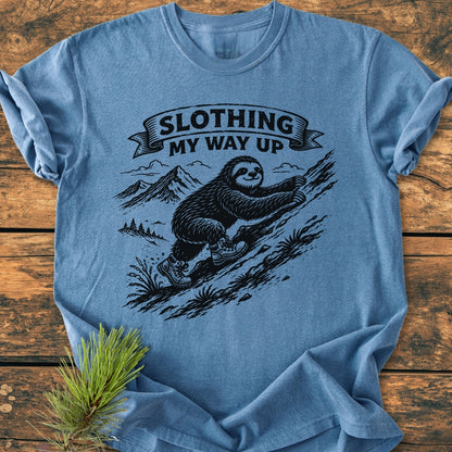 Slothing My Way Up - Vintage Wash Tee features a sloth climbing a slope with a playful slogan. The heather-blue tee is soft, durable, and ideal for everyday wear.