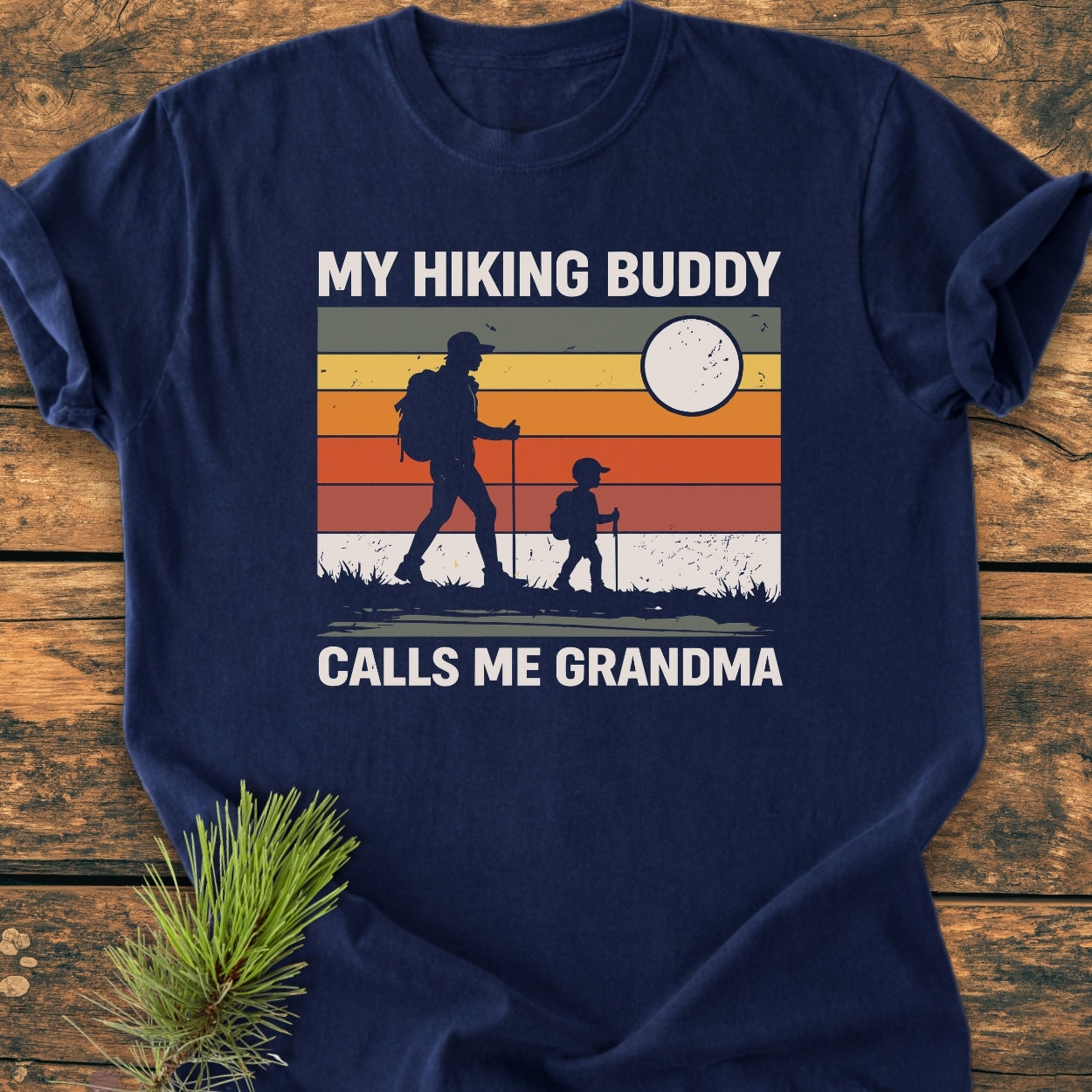 My Hiking Buddy Calls Me Grandma - Vintage Wash Tee features a retro hiking graphic with figures and text on a navy-blue, soft-washed, relaxed fit T-shirt, perfect for casual comfort.
