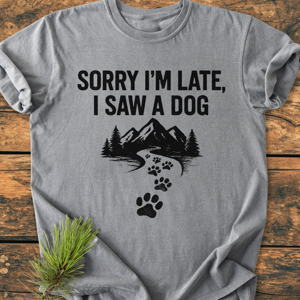 Sorry I'm Late - Vintage Wash Tee: Heather-gray t-shirt with bold text and mountain graphic, featuring a cozy, relaxed fit made from soft, pre-shrunk ring-spun cotton, displayed with a pine sprig.