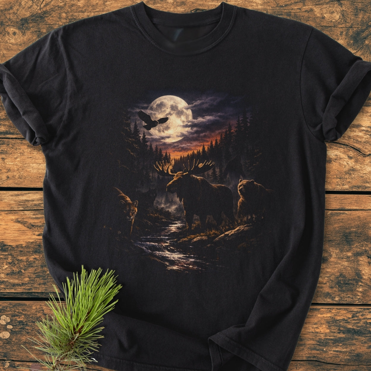 Moonlit Woodland - Vintage Wash Tee features a stylized forest scene with a full moon, owl, moose, bear, and mountain lion, all printed on a black garment-dyed T-shirt.
