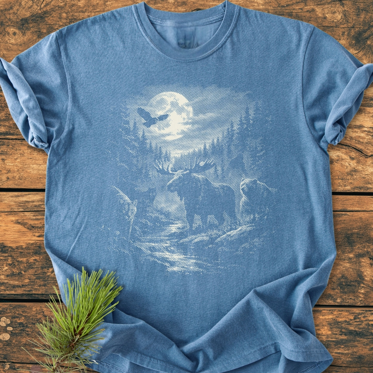 Moonlit Woodland - Vintage Wash Tee: Heather-blue T-shirt with a woodcut-style scene of a moonlit pine forest, flying bird, and moose. Made from 100% ring-spun cotton, ideal for comfort and durability.