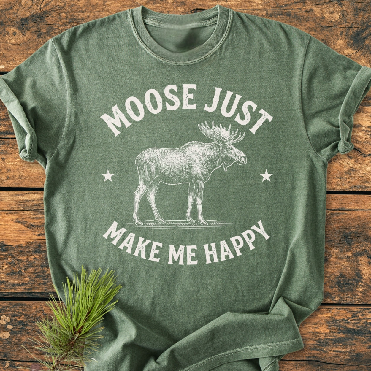 Moose Make Me Happy - Vintage Wash Tee featuring a detailed moose line-drawing and stars, laid flat with pine sprig beside. Comfortable, garment-dyed, relaxed fit, ideal for daily wear.