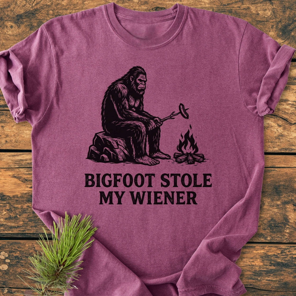 Bigfoot Stole My Wiener - Vintage Wash Tee features a playful Bigfoot illustration by a campfire on a purple-heather T-shirt, enhanced with a cozy, relaxed fit and durable stitching.