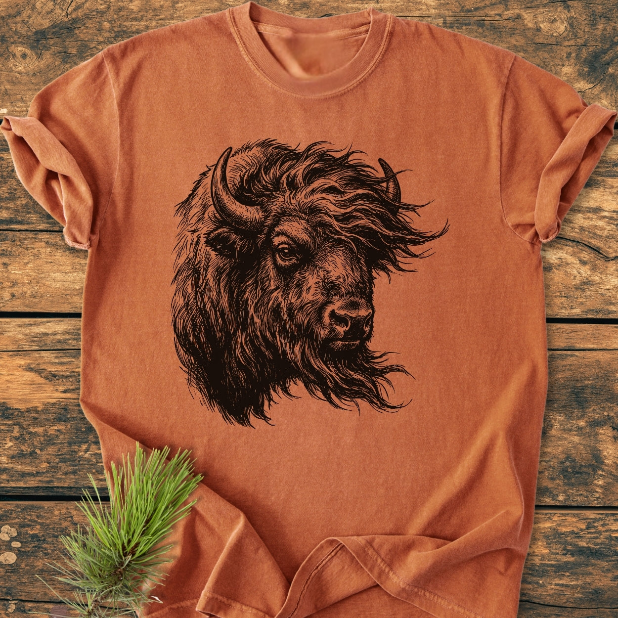 Silent Thunder - Vintage Wash Tee features a hand-drawn bison portrait on a soft, relaxed fit, orange-rust T-shirt, laid flat on a wooden surface, enhanced by durable double-needle stitching.