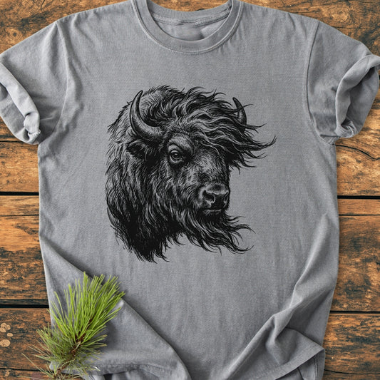 Silent Thunder - Vintage Wash Tee featuring a black bison head illustration on a heather-gray, soft-washed, short-sleeve shirt, styled with a pine sprig on a wooden surface.