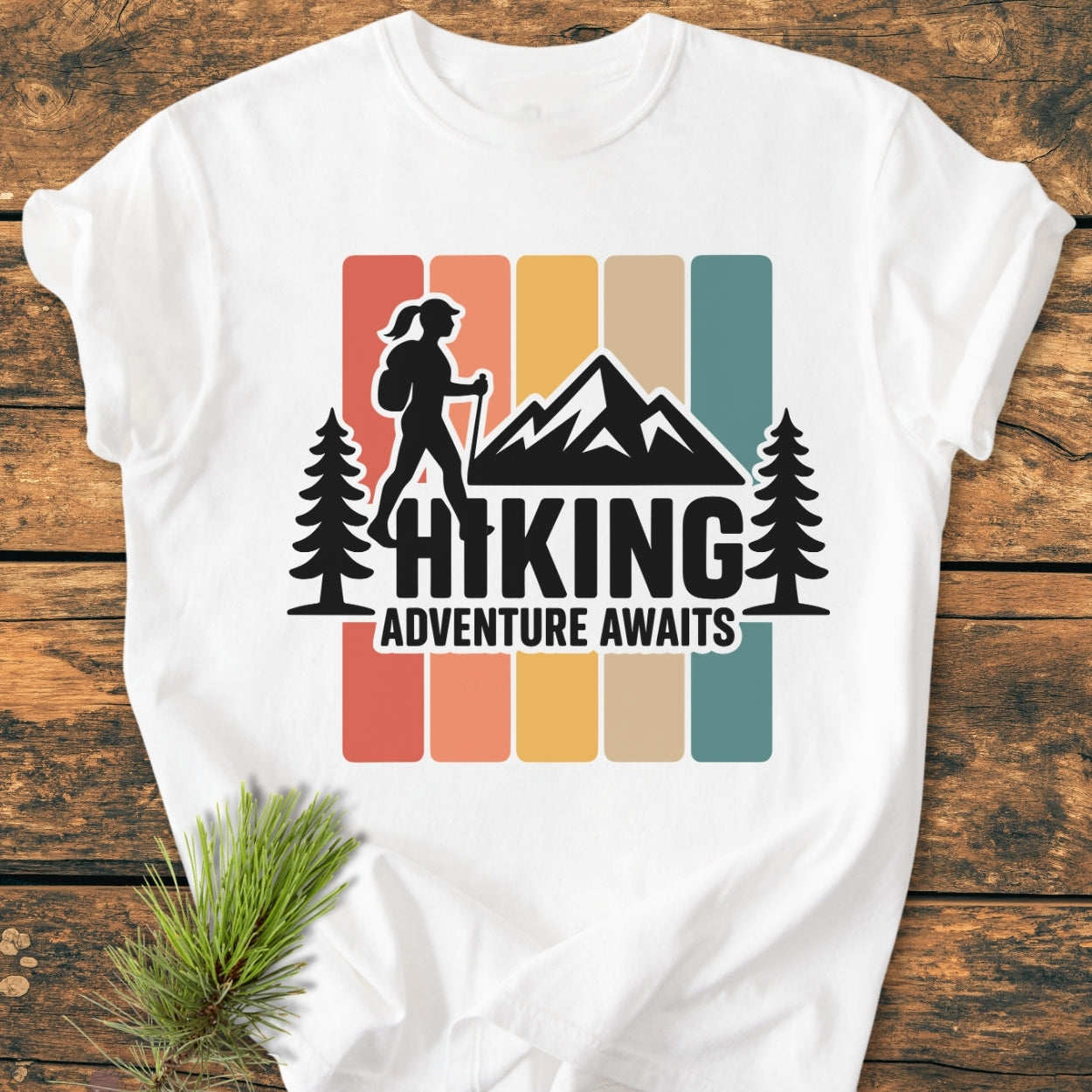 Hiking Girl - Vintage Wash Tee featuring a retro graphic of a hiker, pine trees, and mountains, laid on wood. Made from soft, durable 100% ring-spun cotton, perfect for daily wear.