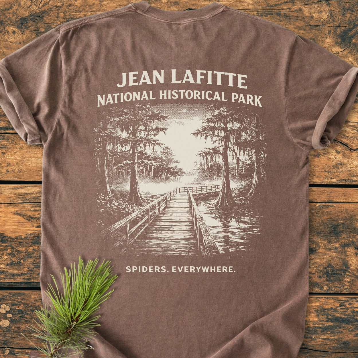 Spiders. Everywhere. BACK PRINT - Vintage Wash Tee features a boardwalk through a cypress swamp on a brown T-shirt, highlighting the Jean Lafitte National Park theme with a humorous tagline.
