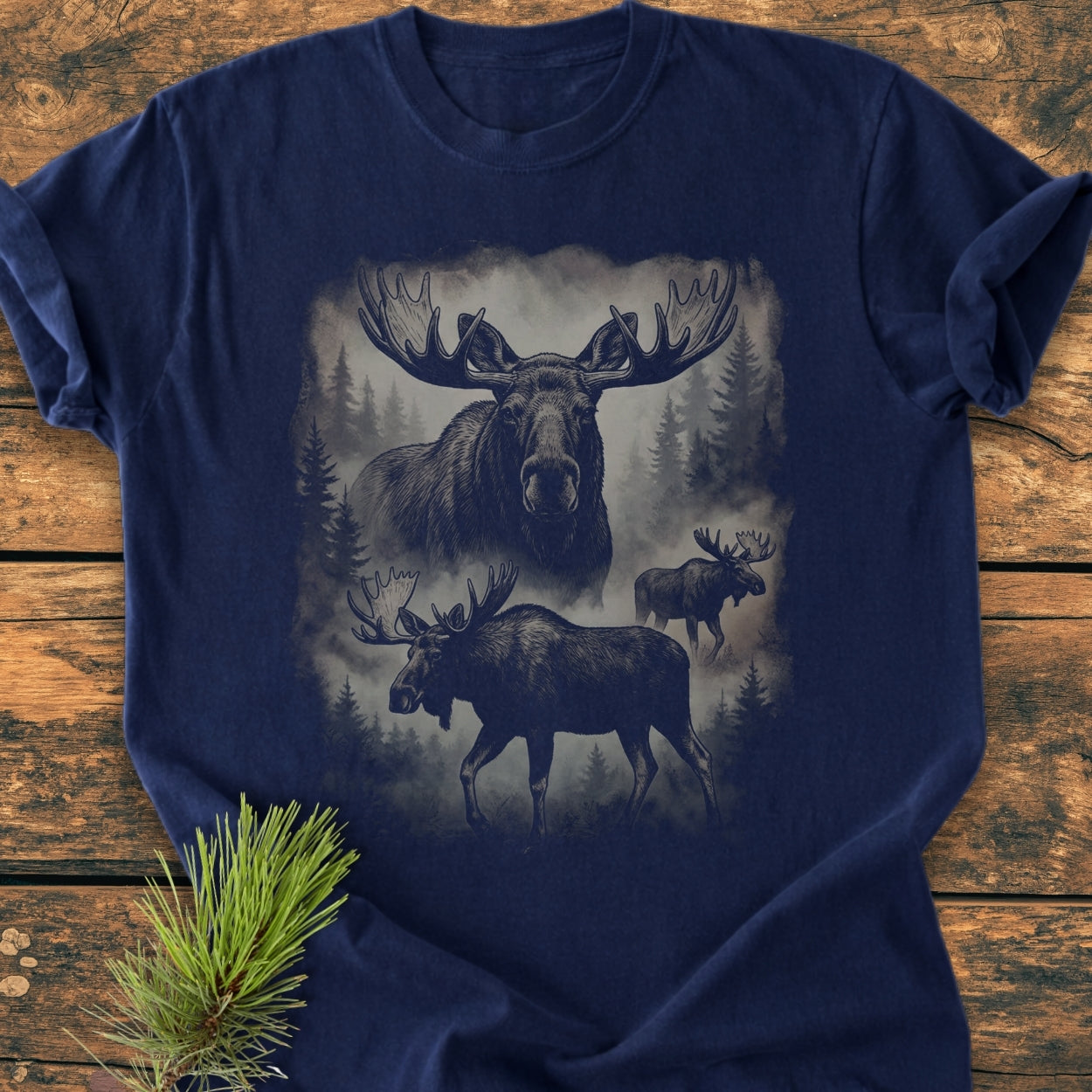 Shadow Moose - Vintage Wash Tee features a misty forest scene with three moose illustrations on a navy-blue T-shirt, highlighting a bull moose head, full-body moose, and distant moose amid swirling fog.
