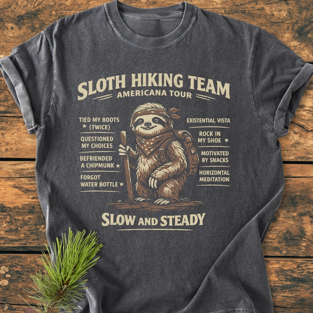 Sloth Hiking Team Tour - Vintage Wash Tee features a cartoon sloth with hiking gear and playful bullet points on a charcoal-gray background, emphasizing humor and a relaxed fit.