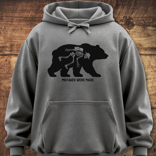 Mistakes Were Made Hoodie: Gray sweatshirt with a black bear silhouette revealing a cartoon skeleton hiker, features a cozy fit, jersey-lined hood, and front pouch pocket, perfect for outdoor adventures.