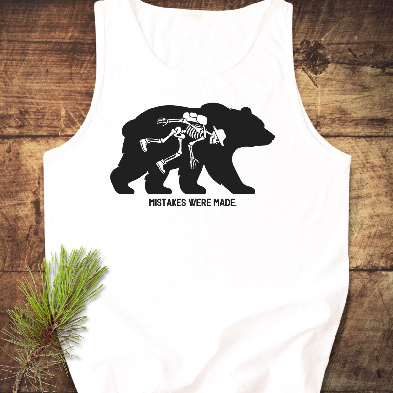 Mistakes Were Made Tank Top features a black bear graphic with a hiker skeleton inside, captioned below. It's a unisex, garment-dyed tank made from sustainable US cotton, offering a relaxed fit.