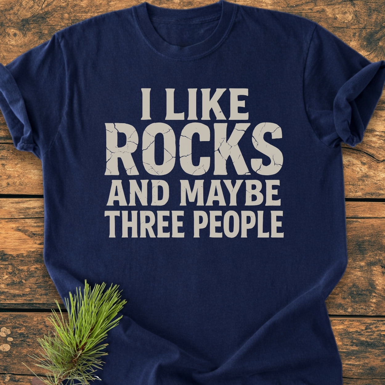 I Like Rocks - Vintage Wash Tee, navy-blue with light-gray block letters, laid flat on wood. Made from garment-dyed, soft-washed, 100% ring-spun cotton for a cozy, relaxed fit.