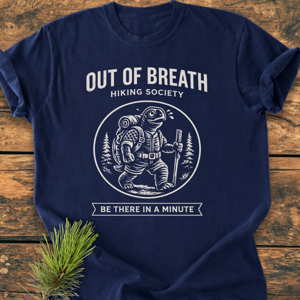 Out Of Breath Turtle - Vintage Wash Tee featuring a turtle logo with hiking gear, laid flat on a wooden surface, showcases a relaxed fit and durable design with a soft, pre-shrunk cotton fabric.