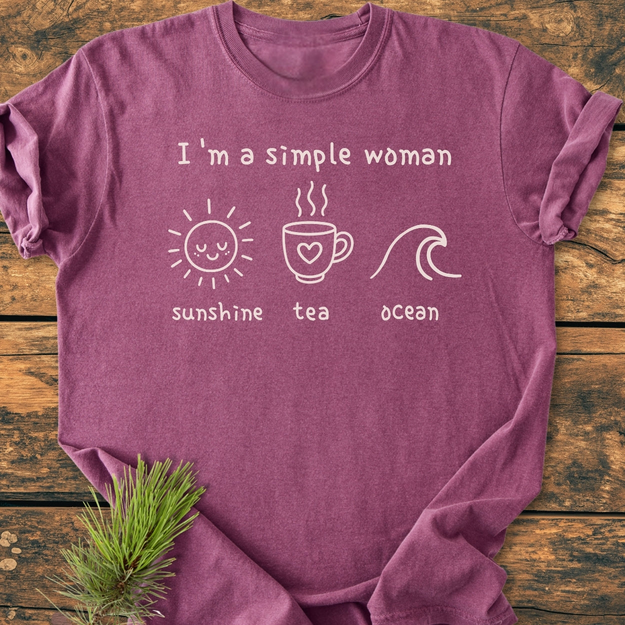 I'm A Simple Woman - Sunshine Tea Ocean - Vintage Wash Tee laid flat, showcasing white graphics and text on mauve fabric, styled with a pine sprig on rustic wood.