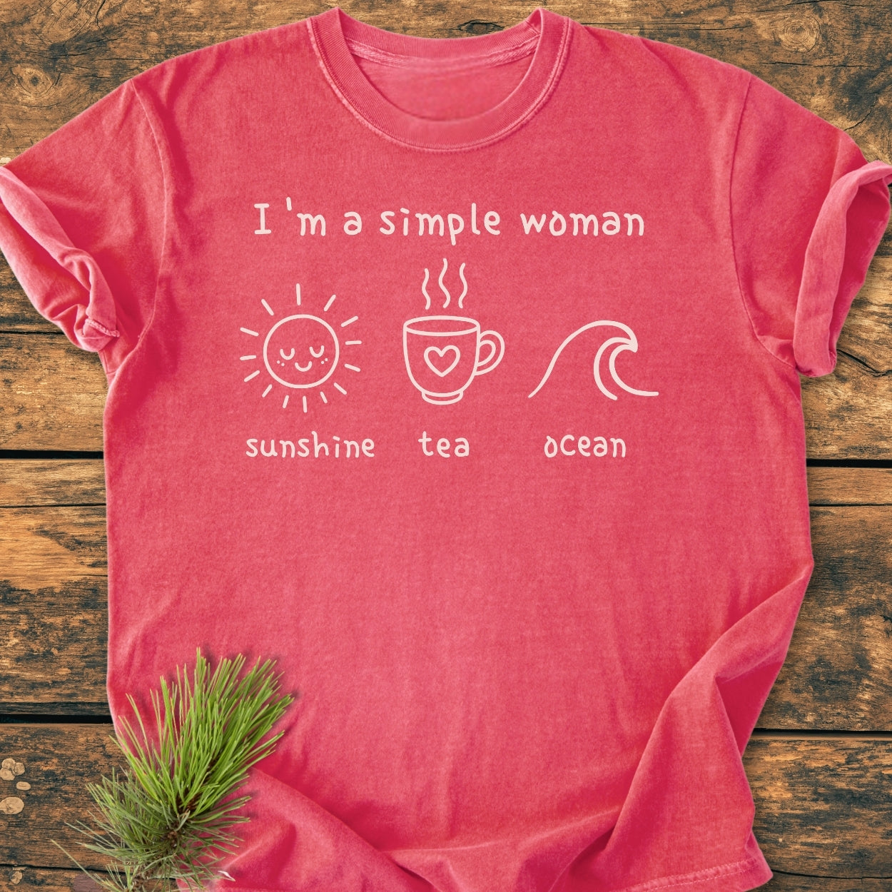 I'm A Simple Woman - Sunshine Tea Ocean - Vintage Wash Tee, featuring white text and icons, laid on wood. A small evergreen sprig accents this soft, relaxed-fit, garment-dyed cotton T-shirt.