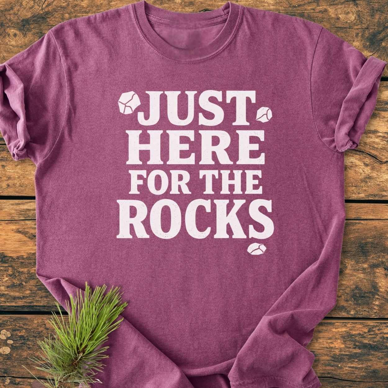 Heathered purple Just Here For The Rocks - Vintage Wash Tee with ice cube graphics, laid flat on wood. Features bold white text, pine sprig accent, showcasing cozy, relaxed fit, and durable stitching.