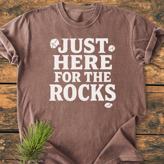 Just Here For The Rocks - Vintage Wash Tee, featuring white text and rock icons, laid on wood. Made from cozy ring-spun cotton, with a relaxed fit and durable double-needle stitching.