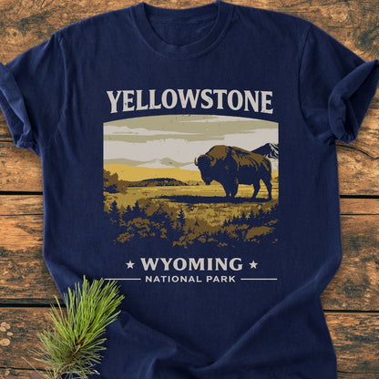 Yellowstone - Vintage Wash Tee featuring a bison graphic with mountains, YELLOWSTONE text above, and WYOMING NATIONAL PARK below, laid on wood with a pine sprig, showcasing its relaxed fit and durability.