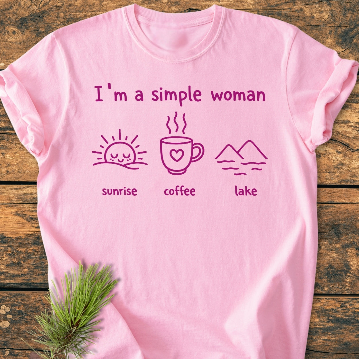 I'm A Simple Woman - Sunrise Coffee Lake - Vintage Wash Tee on wooden surface, featuring playful font and icons of sunrise, coffee, and lake. Cozy, relaxed fit with durable, soft-washed fabric.