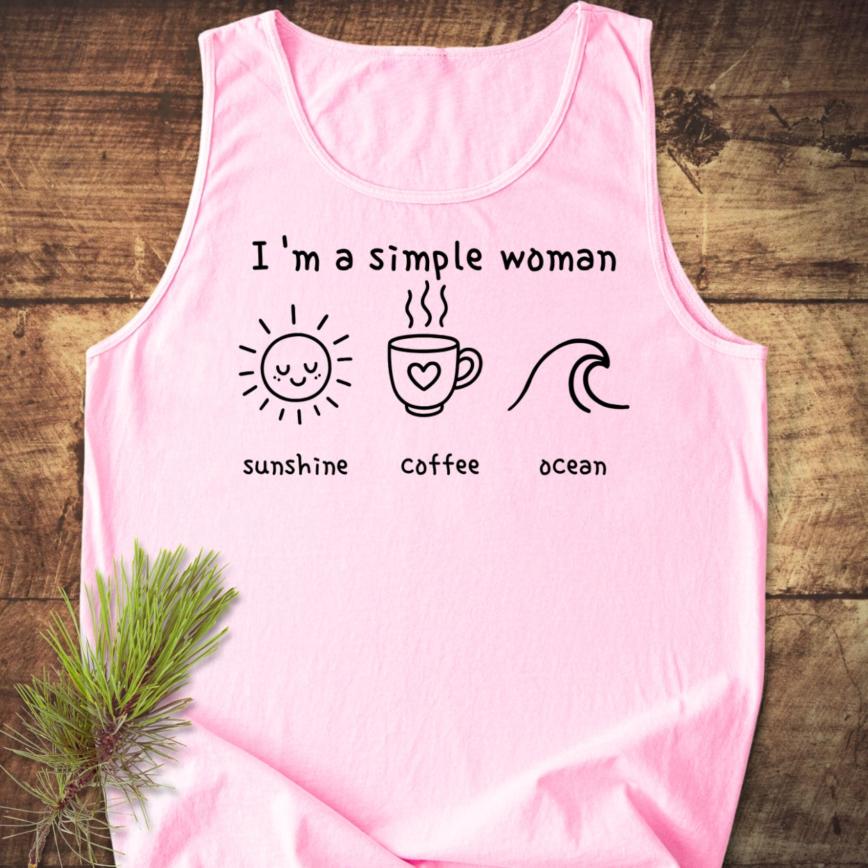 I'm a Simple Woman - Sunshine Coffee Ocean Tank Top featuring black text and icons of a sun, coffee mug, and ocean wave, laid flat on a wooden surface.