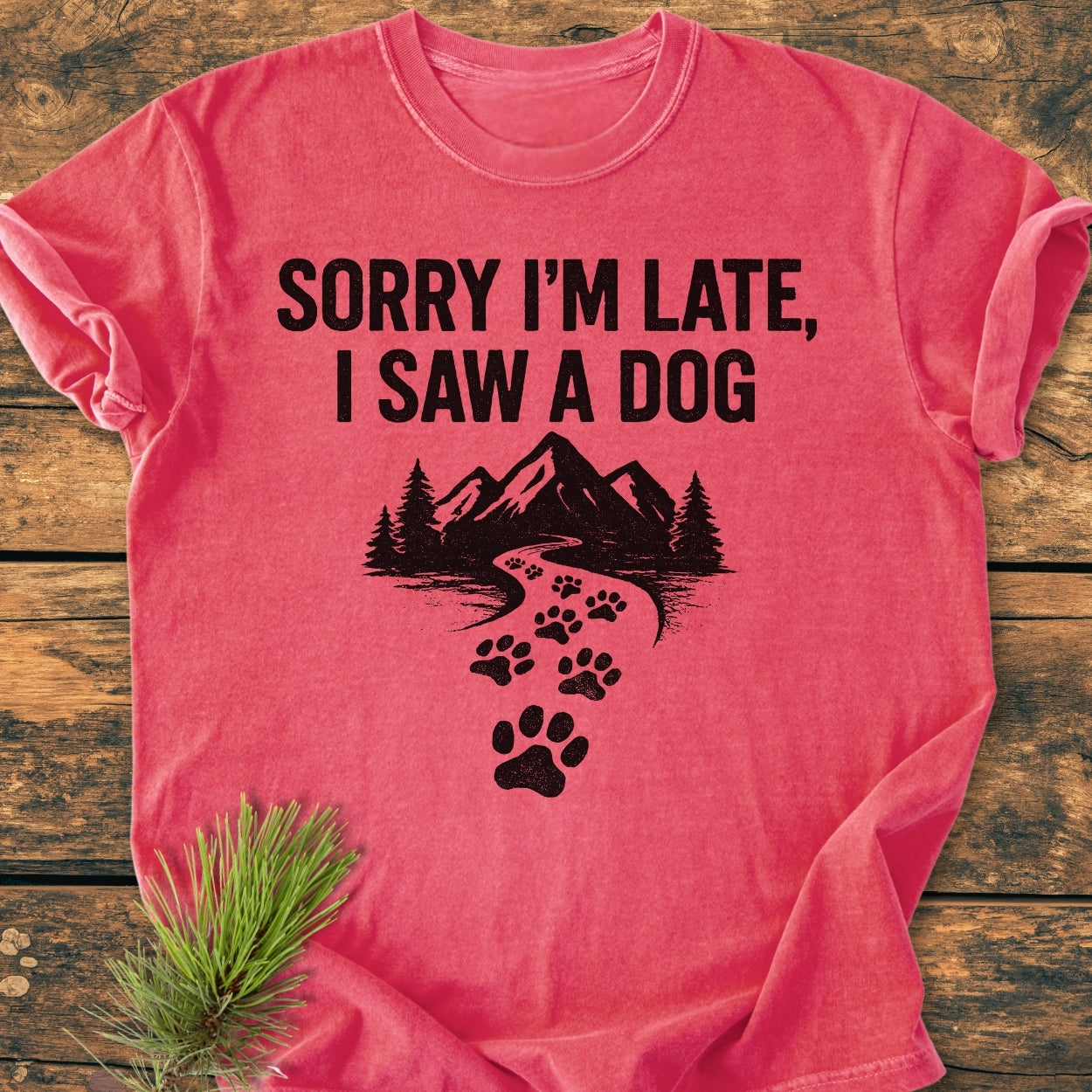 Sorry I'm Late - Vintage Wash Tee featuring bold text and a scenic graphic with paw prints, laid on a wooden surface. Crafted from soft, durable, pre-shrunk 100% ring-spun cotton for comfort.