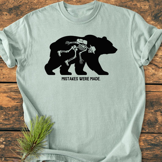 Mistakes Were Made - Vintage Wash Tee features a mint T-shirt with a black bear silhouette, revealing a white-line hiker skeleton inside, and the phrase MISTAKES WERE MADE beneath in bold letters.