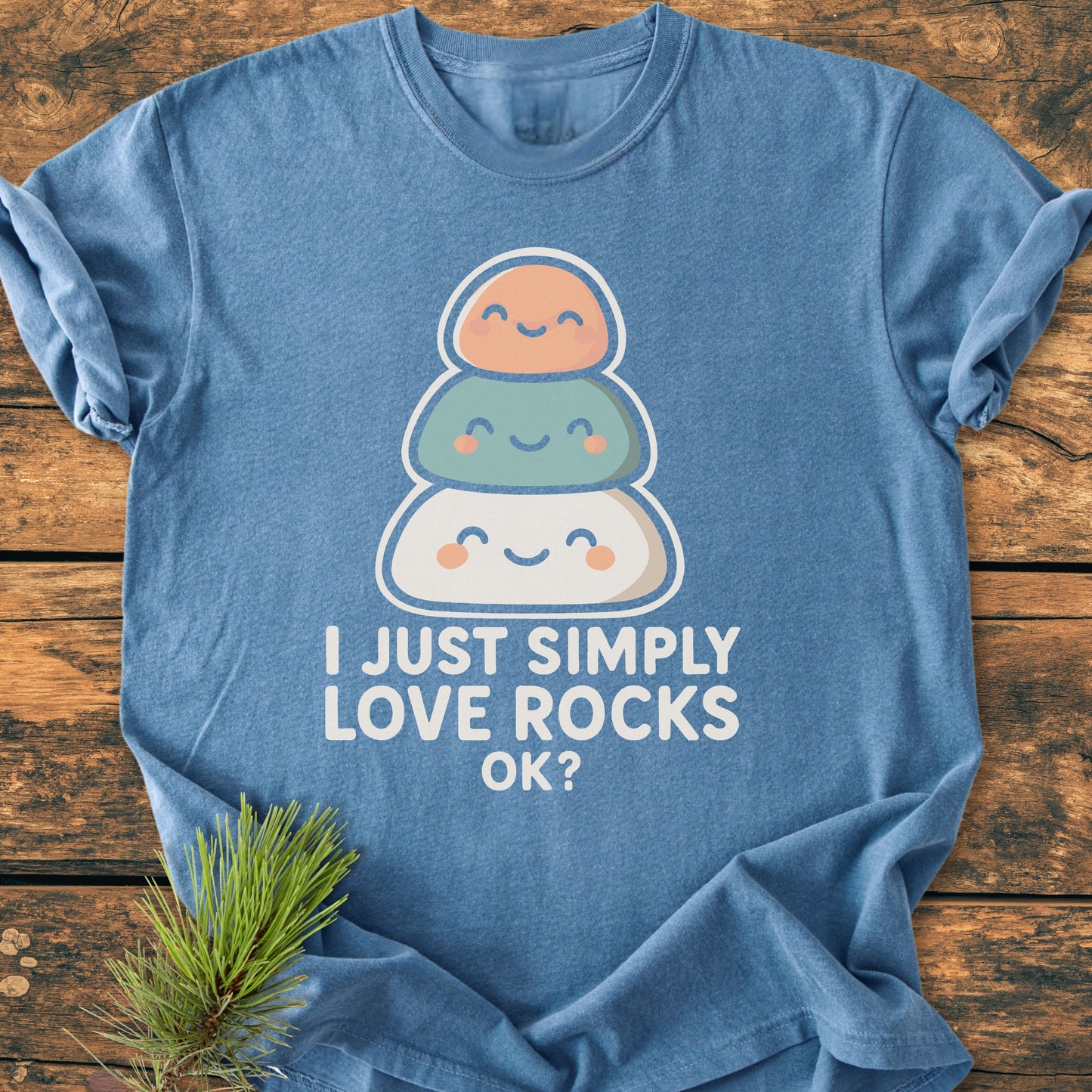 The I Just Simply Love Rocks OK? - Vintage Wash Tee features a cartoon of smiling stacked rocks with playful text, presented on a heather-blue background, highlighting its relaxed fit and cozy fabric.