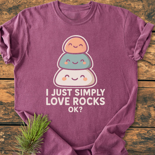 I Just Simply Love Rocks OK? - Vintage Wash Tee features a cute graphic of smiling rocks with a quirky slogan, laid on wood with a pine sprig for a rustic touch.