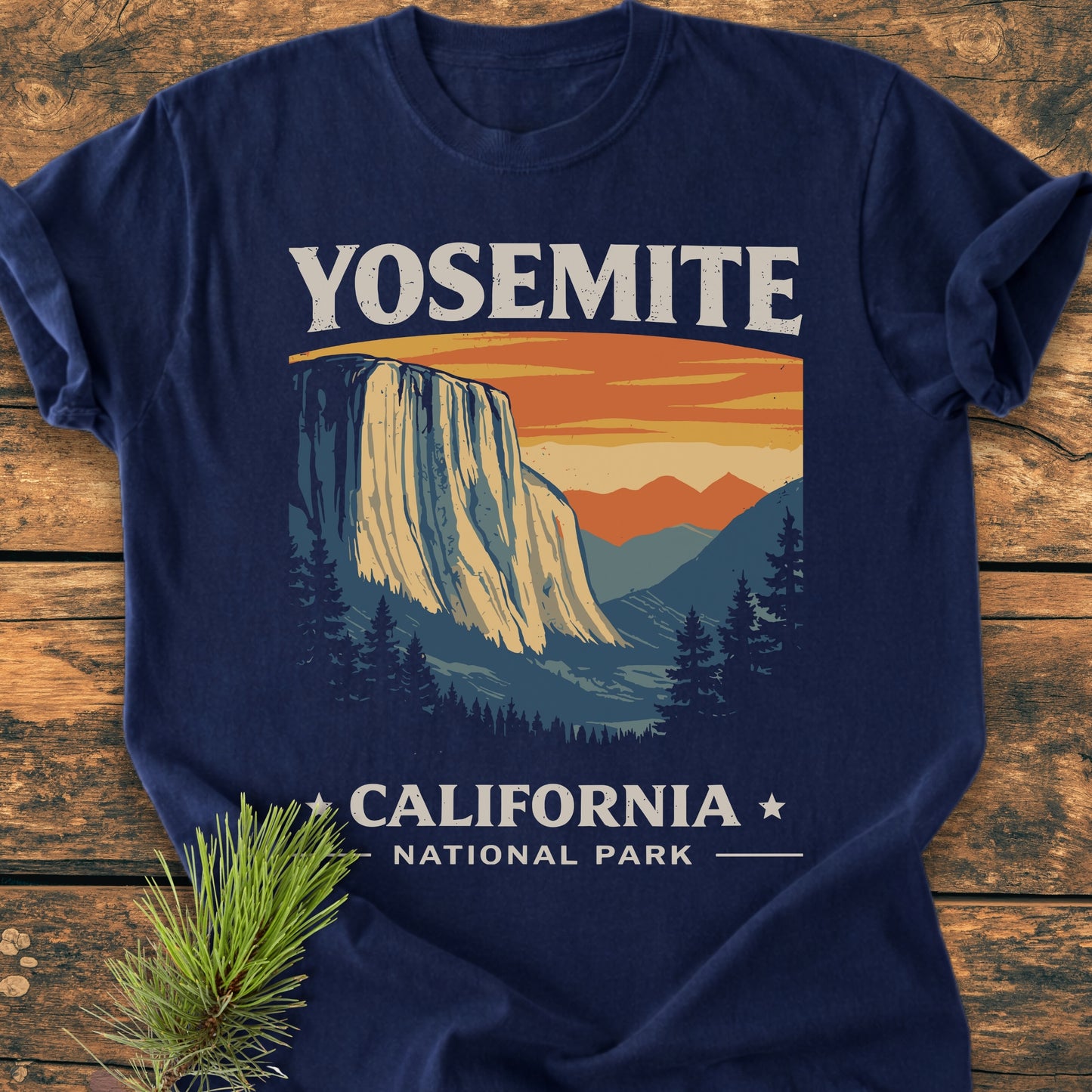 Yosemite National Park - Vintage Wash Tee features a stylized Yosemite scene print on a navy-blue T-shirt, laid on rustic wood, showcasing its relaxed fit and soft-washed, durable fabric.