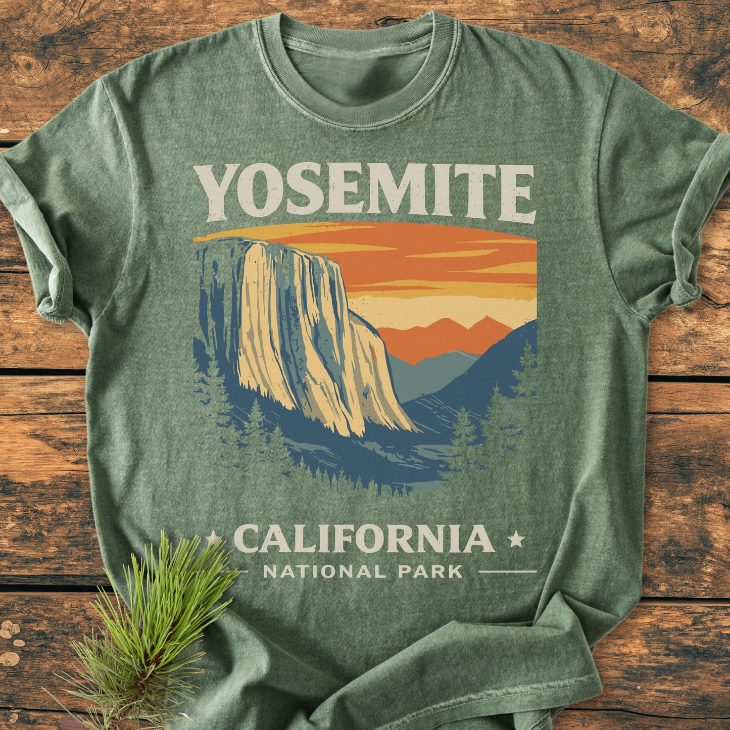 Yosemite National Park - Vintage Wash Tee featuring Yosemite's granite cliffs graphic, laid on wood. The soft green, relaxed-fit, garment-dyed T-shirt offers comfort with double-needle stitching for durability.