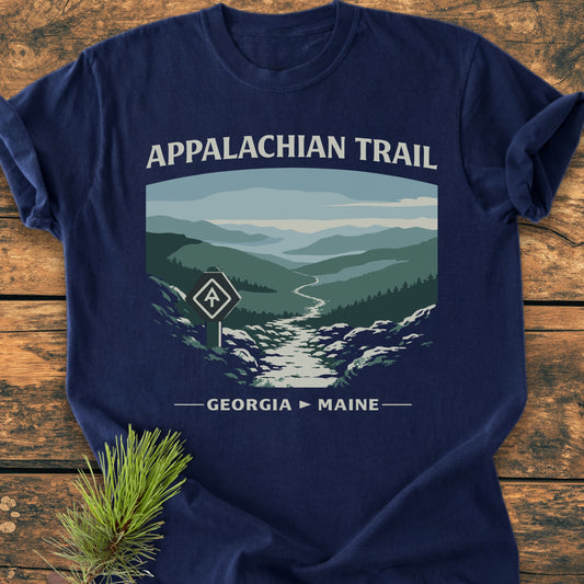Appalachian Trail - Vintage Wash Tee featuring a stylized mountain valley and trail graphic with “GEORGIA → MAINE” text, laid on wood. Made of soft, pre-shrunk ring-spun cotton for comfort.
