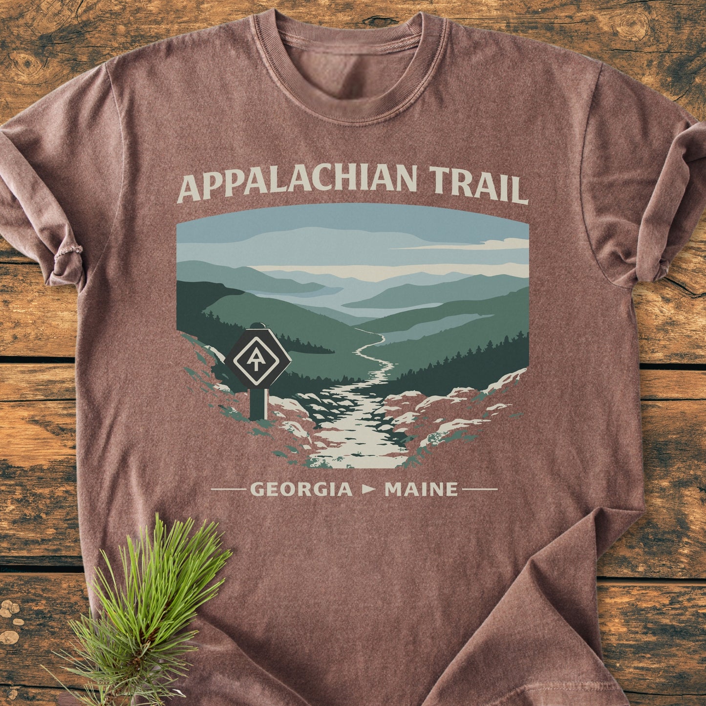 Appalachian Trail - Vintage Wash Tee featuring a mountain landscape and trail design, set on wood with pine branch, showcasing a relaxed fit and soft, garment-dyed cotton fabric for comfort.