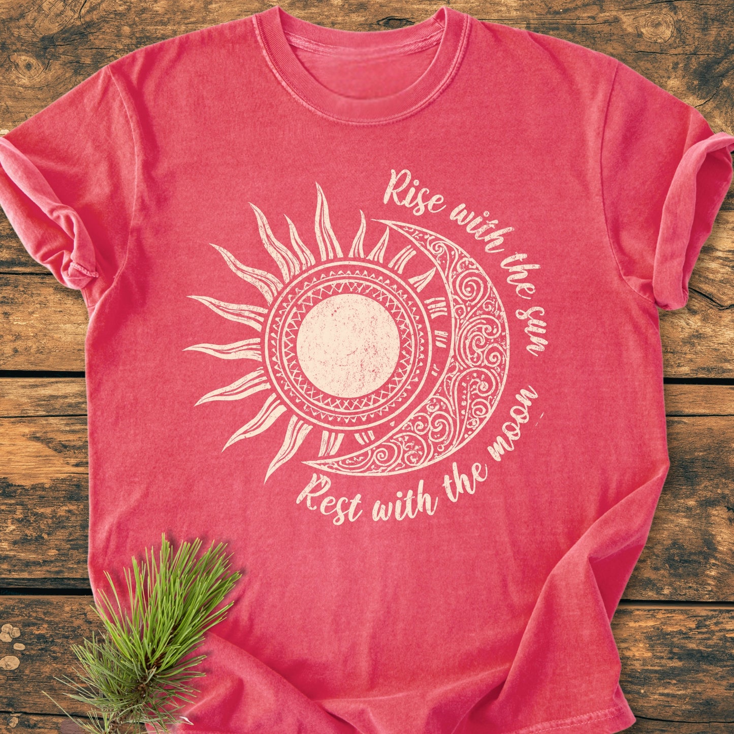 Sun & Moon Mystical Boho - Vintage Wash Tee featuring a stylized half-sun/half-moon graphic with motivational text, laid flat on wood with pine needles accent, showcasing its relaxed fit and durable stitching.