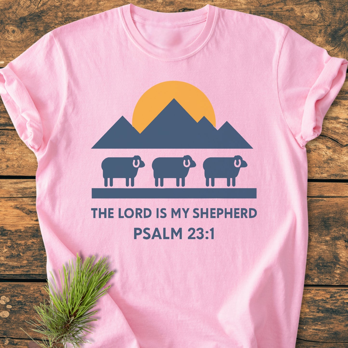 The Lord Is My Shepherd - Vintage Wash Tee features a graphic of three sheep under mountains and sun, with THE LORD IS MY SHEPHERD and PSALM 23:1 printed on soft-washed, ring-spun cotton.