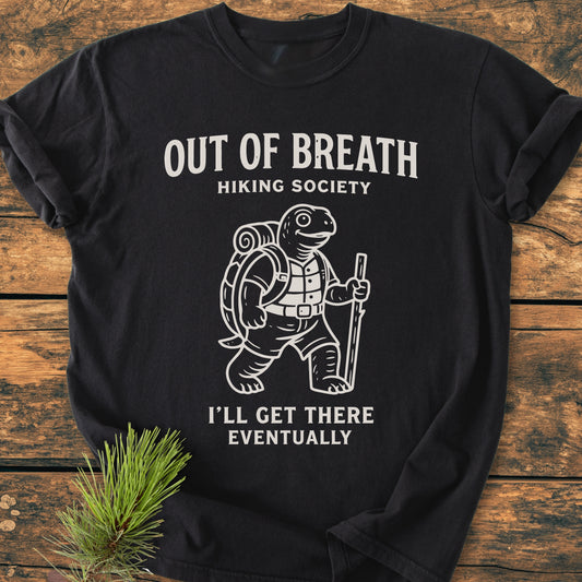 Out Of Breath Turtle - Vintage Wash Tee features a hiking turtle with a sleeping mat and stick, humorously captioned, designed on a soft, durable black T-shirt, enhanced by a pine sprig accent.