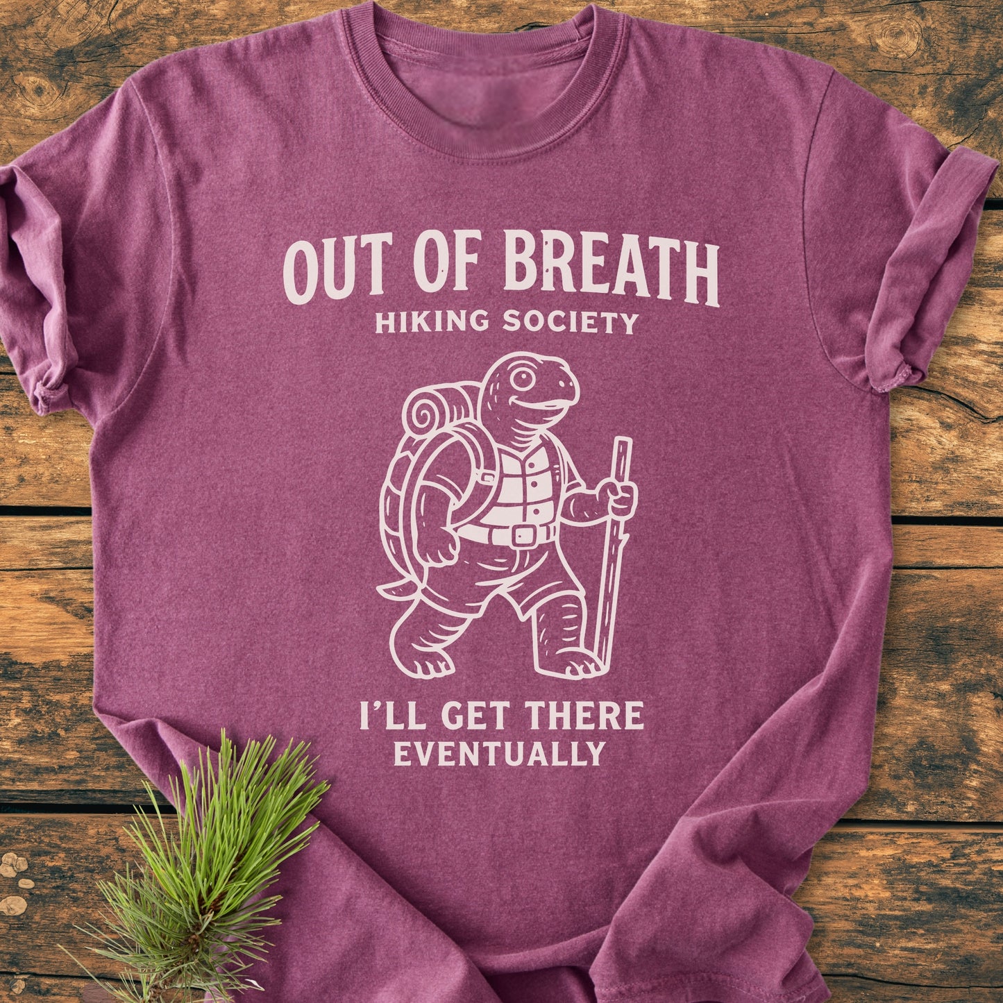 Out Of Breath Turtle - Vintage Wash Tee features a cartoon tortoise in hiking gear with humorous text, laid on wood. Crafted from soft, durable, garment-dyed, 100% ring-spun cotton for a relaxed fit.