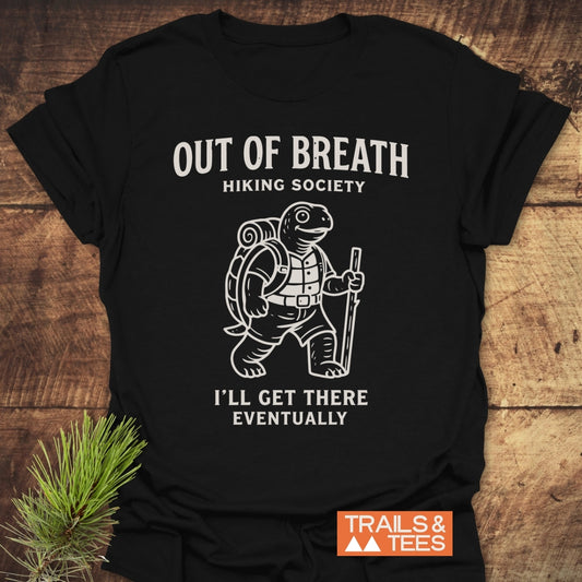Out Of Breath Turtle T-Shirt featuring a cartoon turtle in hiking gear with humorous text, crafted from soft, lightweight cotton. Includes durable print and Trails & Tees logo for outdoor enthusiasts.