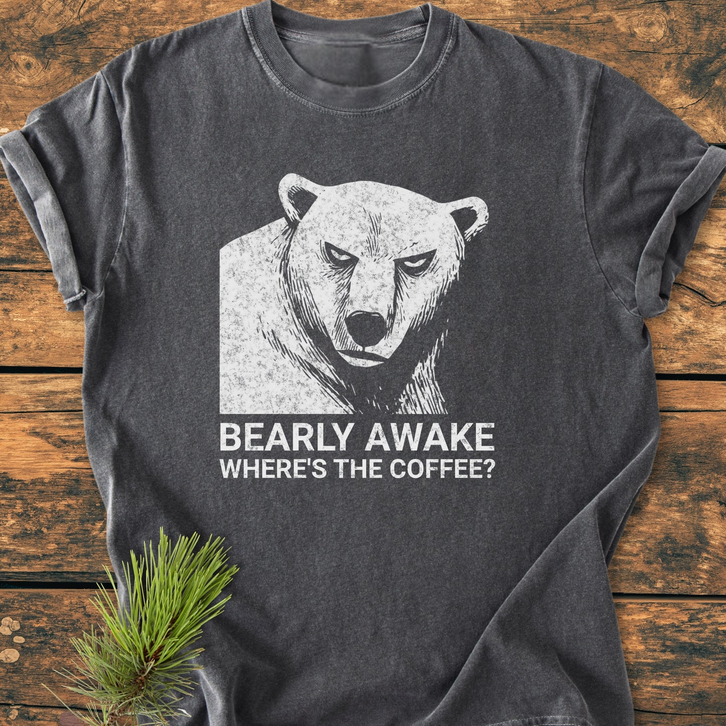 Bearly Awake - Vintage Wash Tee displayed on wood, showcasing a grumpy bear design with the slogan “WHERE’S THE COFFEE?” in white. Features a soft, relaxed fit for everyday comfort.