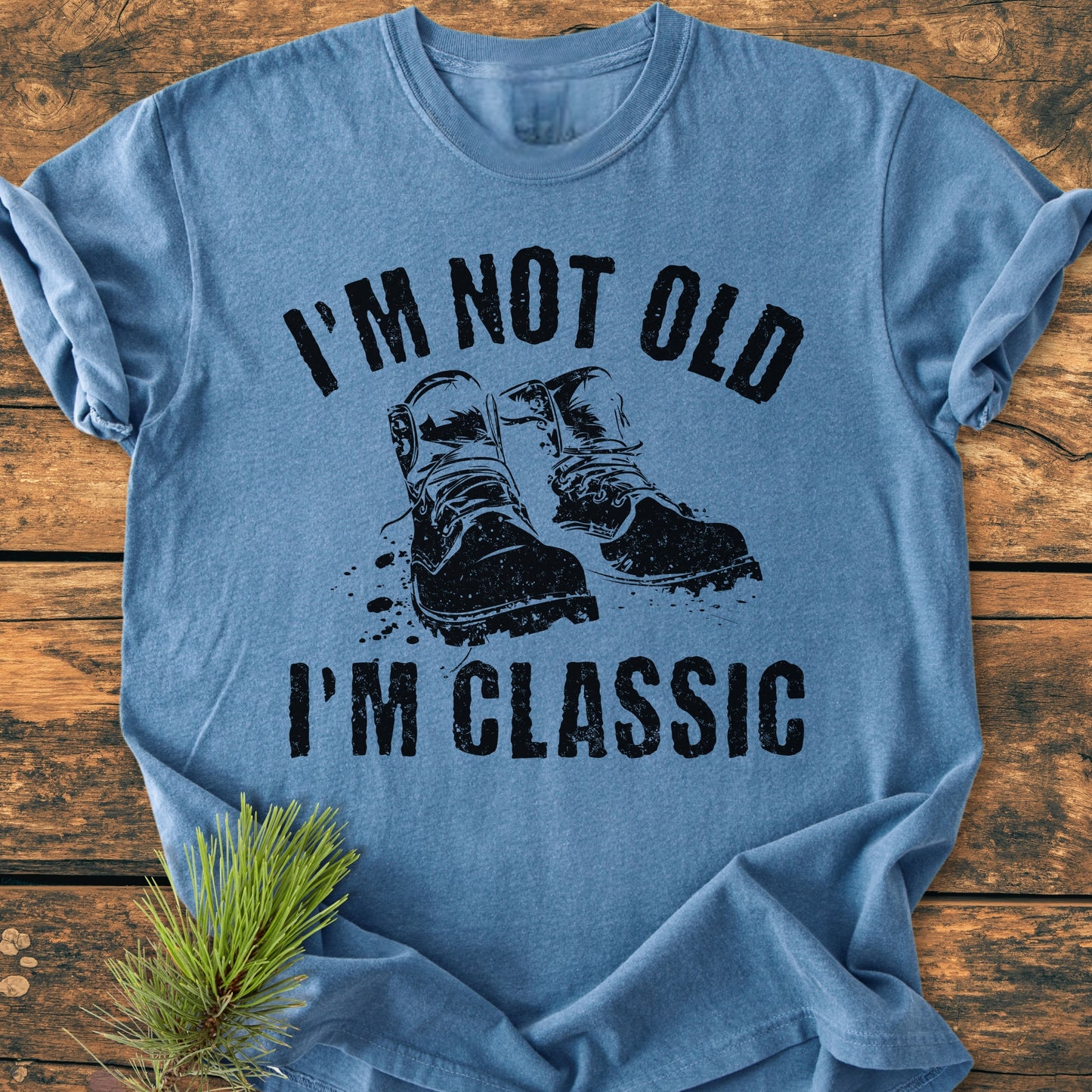 I'm Not Old I'm Classic - Vintage Wash Tee in heather-blue, featuring a double boot graphic and slogan, styled on a wooden surface with pine. Soft, durable, and pre-shrunk for comfort.